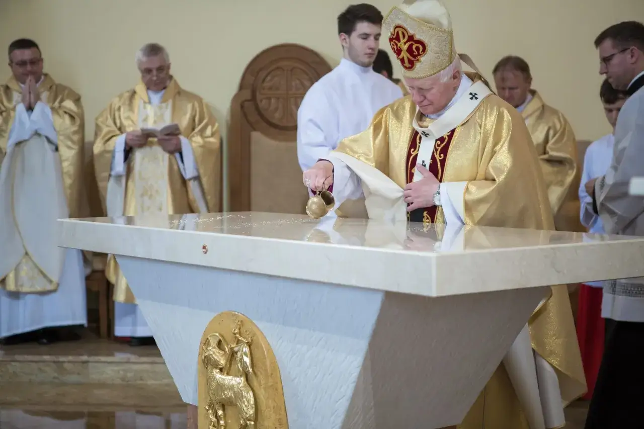 Biskup w złotej szacie polewa ołtarz wodą święconą. To część rytuału, który wyjaśnia, co to jest konsekracja kościoła.