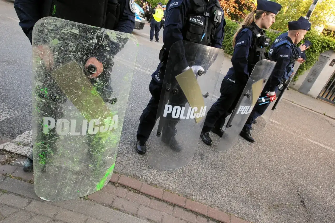 Policjanci w pełnym umundurowaniu, zgodnie z rozporządzeniem, osłaniają się transparentnymi tarczami z napisem 