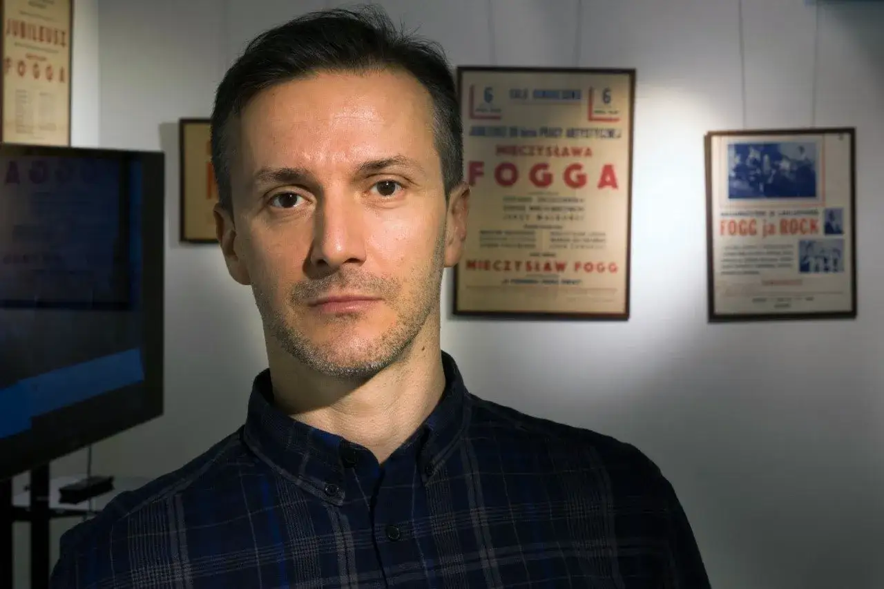 Michał Fogg, prawnuk Mieczysława, stoi przed plakatami upamiętniającymi jego dziadka.