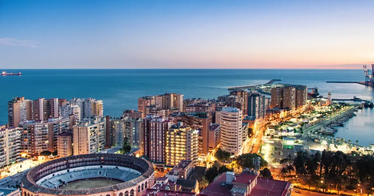 Widok na Malagę nocą z portem, budynkami i areną. Czy Malaga jest bezpieczna? Tak, to piękne i spokojne miasto.