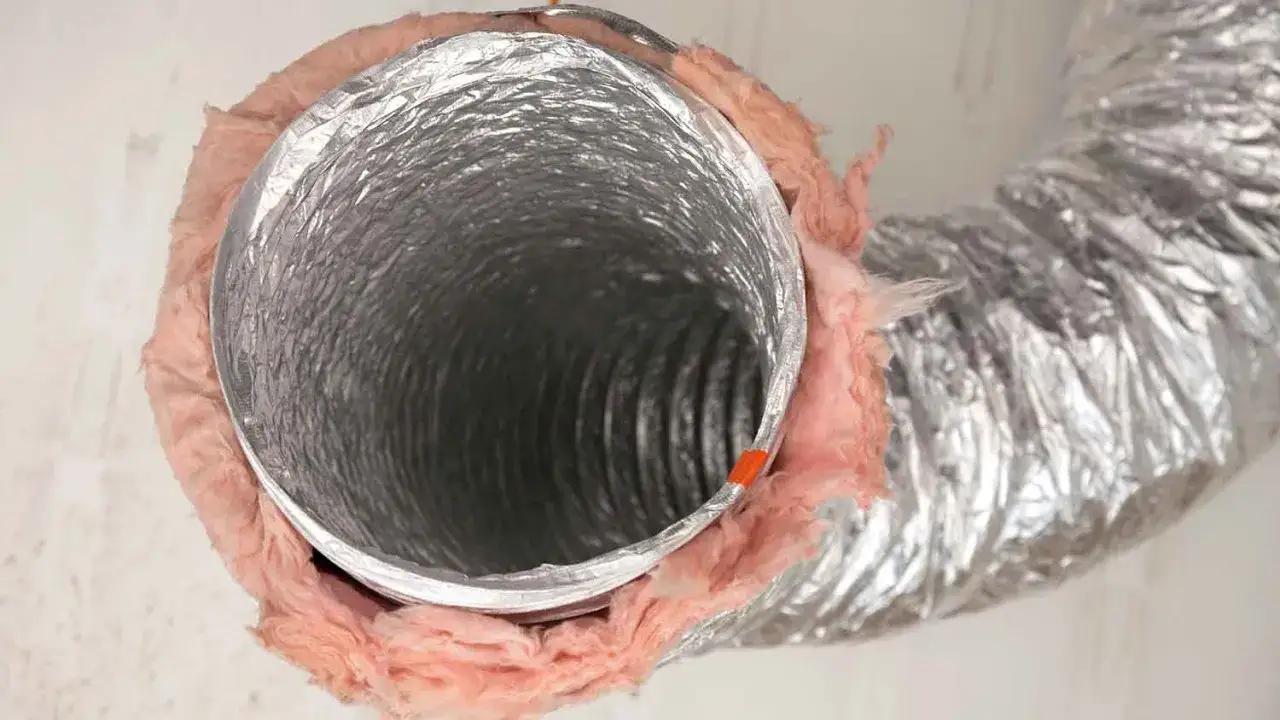 Elastyczny kanał wentylacyjny z folii aluminiowej, owinięty r&oacute;żową wełną mineralną dla izolacji.