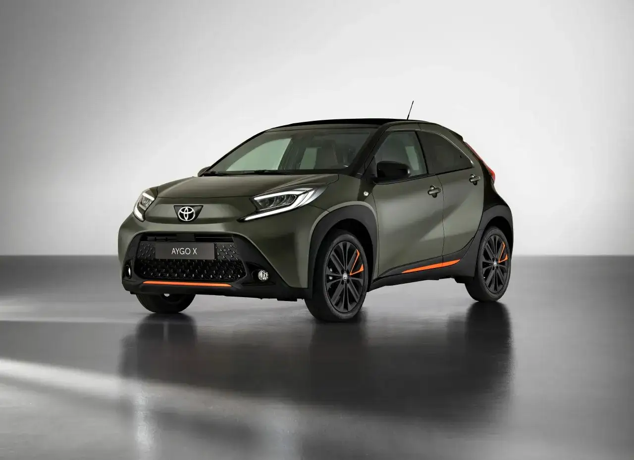 Nowy Toyota Aygo X w kolorze oliwkowym z pomarańczowymi akcentami. Idealny do miasta, dostępny w atrakcyjnym leasingu konsumenckim samochodu.