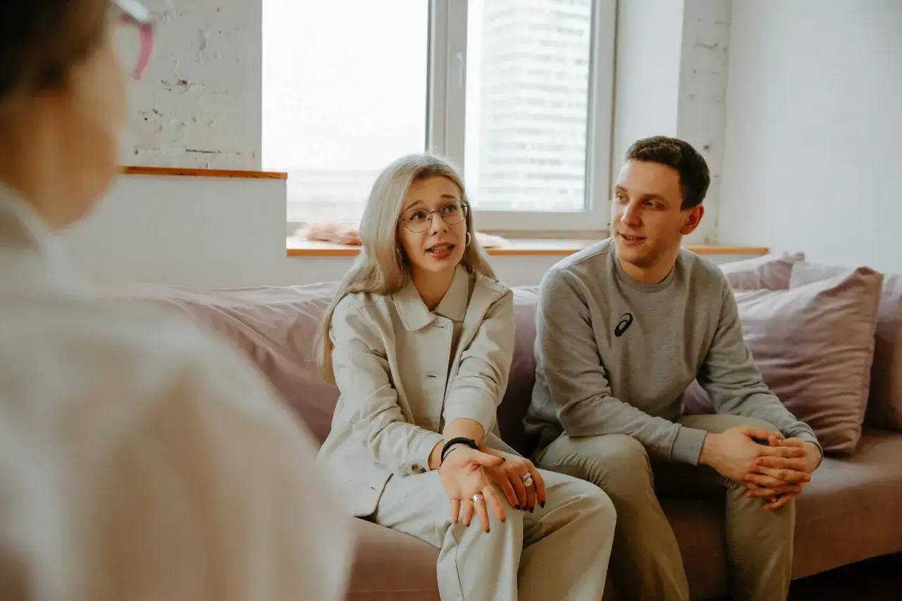 Para rozmawia z terapeutką. Kobieta m&oacute;wi, mężczyzna słucha. To sesja terapii małżeńskiej.