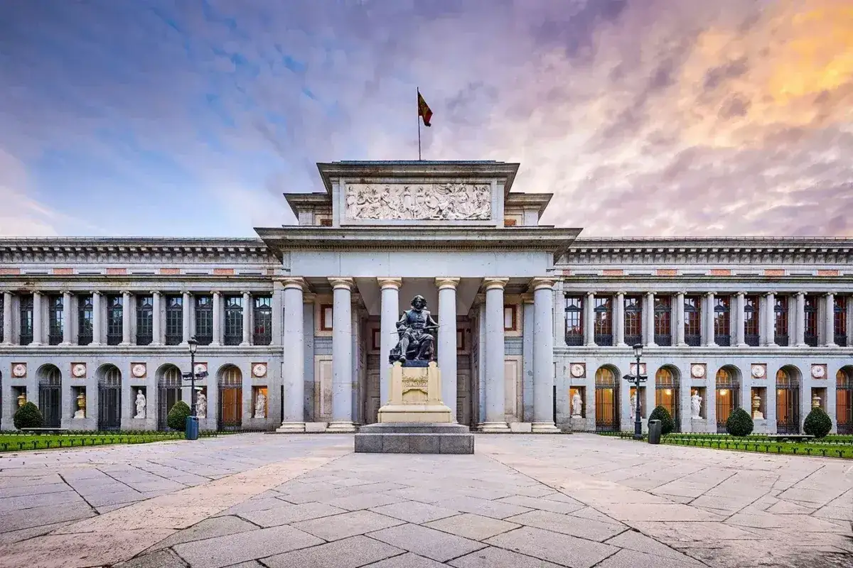 Majestatyczne muzeum sztuki w Madrycie z pomnikiem przed wejściem, pod zachodzącym słońcem.