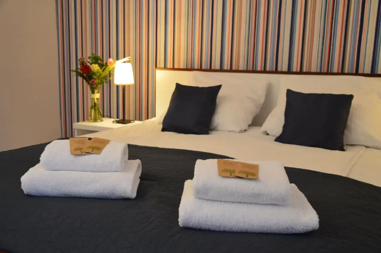 Przytulna sypialnia z bukietem kwiatów i świeżymi ręcznikami. Zastanawiasz się, ile kosztuje nocleg w Krakowie?