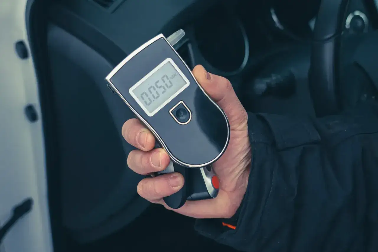 Dłoń trzyma alkomat w samochodzie. Czy pracodawca może sprawdzić pracownika alkomatem? Wynik 0.050.