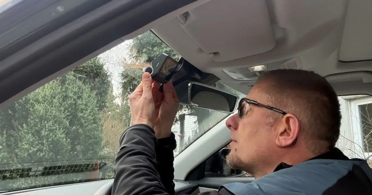 Mężczyzna montuje wideorejestrator w samochodzie. Prosty poradnik, jak podłączyć wideorejestrator, by zwiększyć bezpieczeństwo.