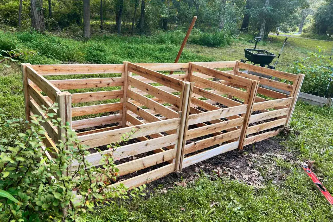 Drewniany kompostownik z trzech sekcji, idealny do ogrodu. Zbudowany z desek, pokazuje, z czego zrobić kompostownik.