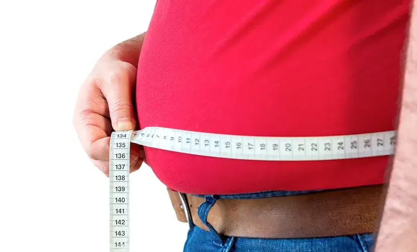 Osoba mierząca obwód w pasie, symbolizująca otyłość brzuszną