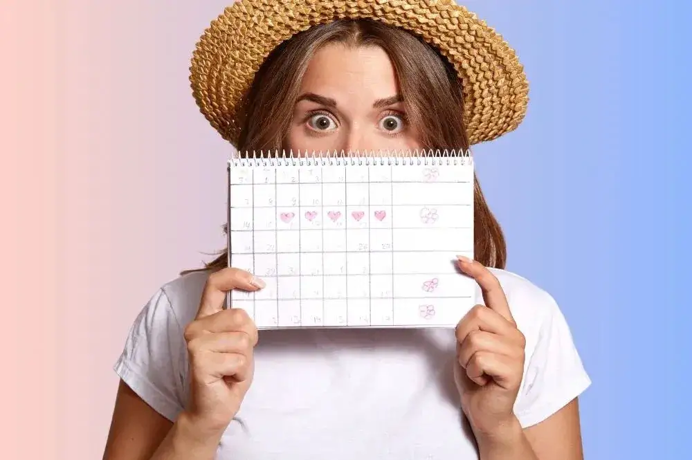 Kobieta z b&oacute;lem brzucha i kalendarzem cyklu menstruacyjnego