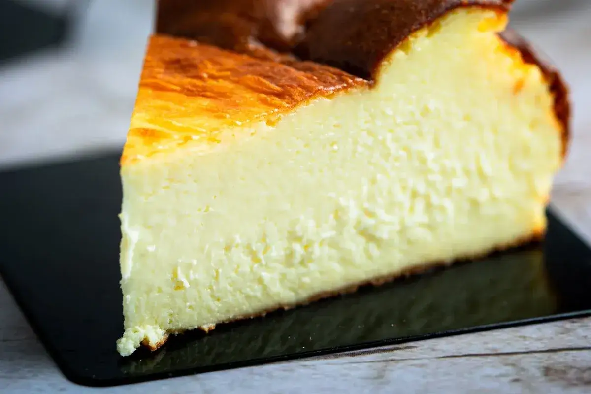 Kawałek kremowego sernika z przypieczoną skórką. Zastanawiasz się, ile waży sernik? Ten wygląda na idealny na deser.