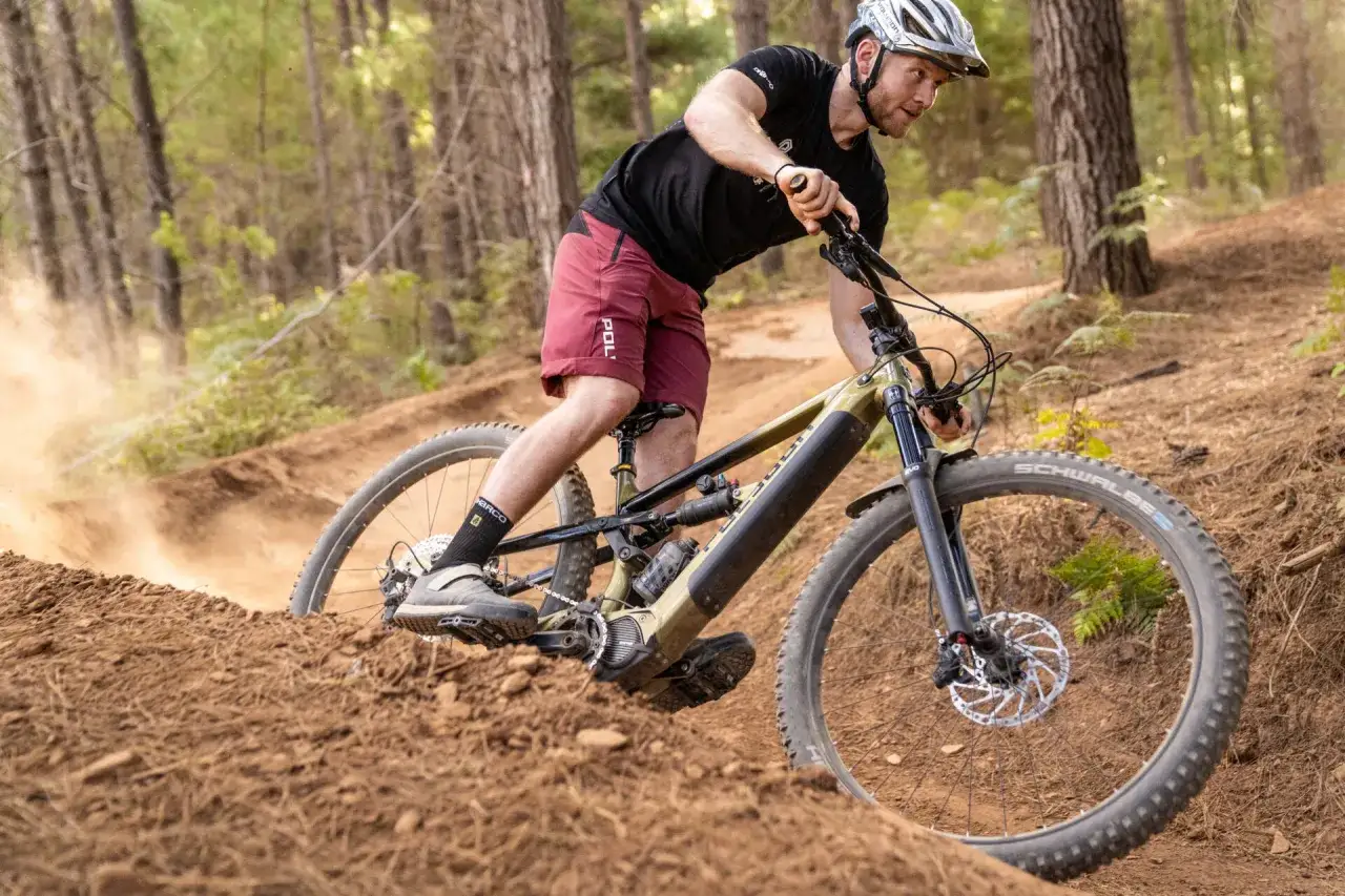 Mężczyzna na rowerze g&oacute;rskim 29 pokonuje zakręt, wzbijając tumany kurzu.