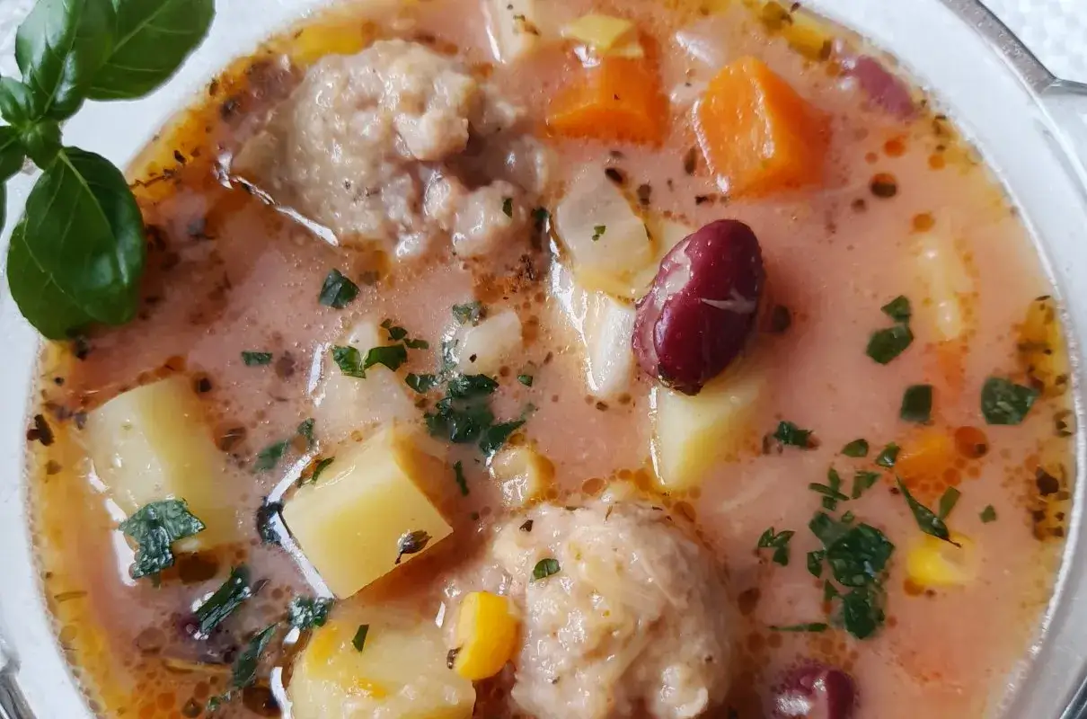 Gęsta zupa meksykańska z pulpecikami, ziemniakami, fasolką i marchewką, posypana natką pietruszki.