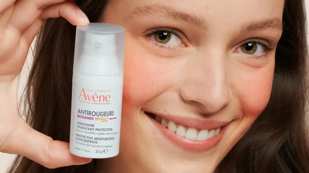 Cera naczynkowa wygląda na zaczerwienioną, jak u uśmiechniętej kobiety z widocznym rumieńcem na policzkach, trzymającej krem.