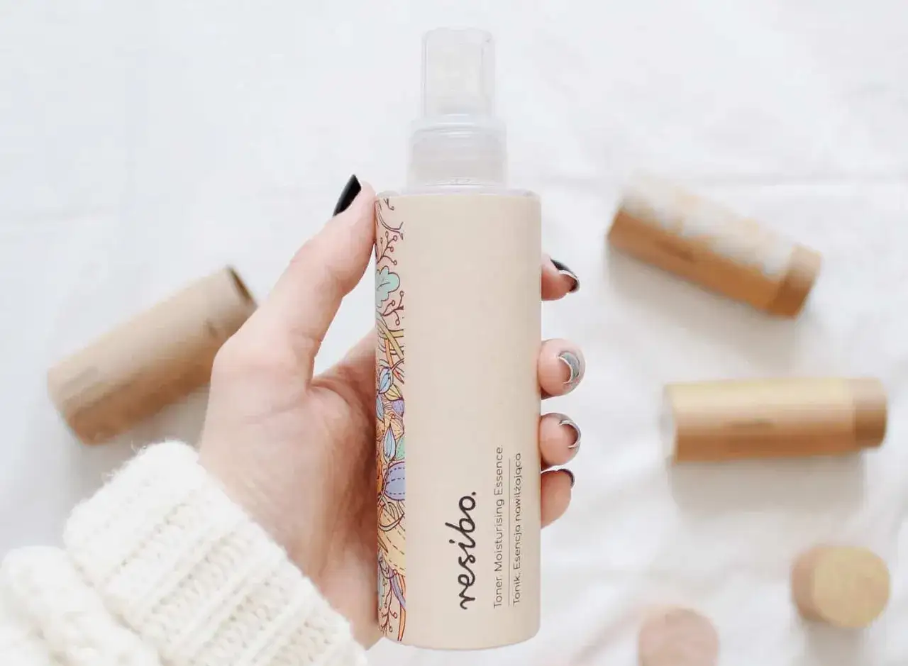 Dłoń trzyma buteleczkę toniku Resibo. Czy tonik trzeba zmywać? Ten nawilżający nie wymaga spłukiwania, pozostawiając skórę odświeżoną.