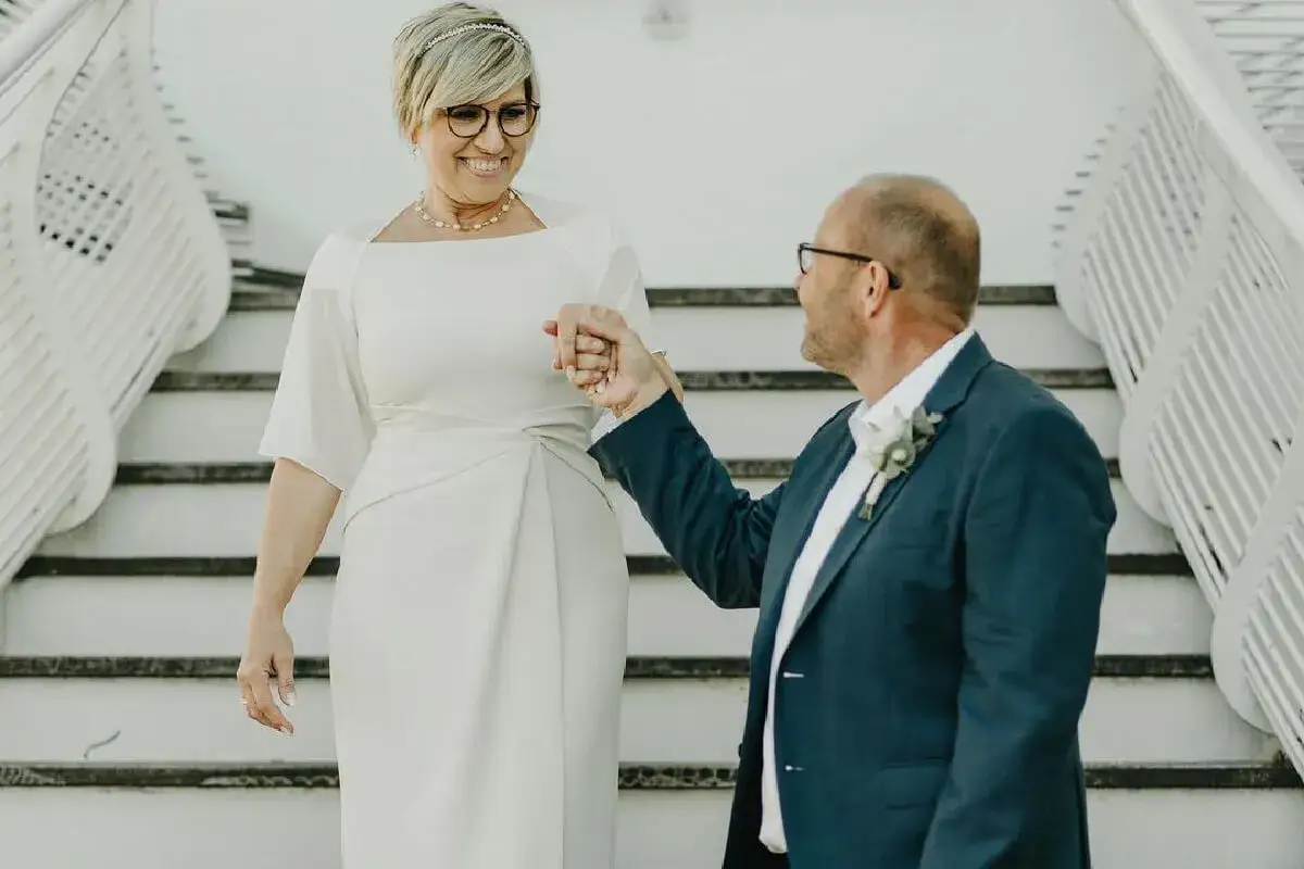 Eleganckie sukienki do ślubu cywilnego dla 50 latki. Para młoda schodzi po schodach, trzymając się za ręce.