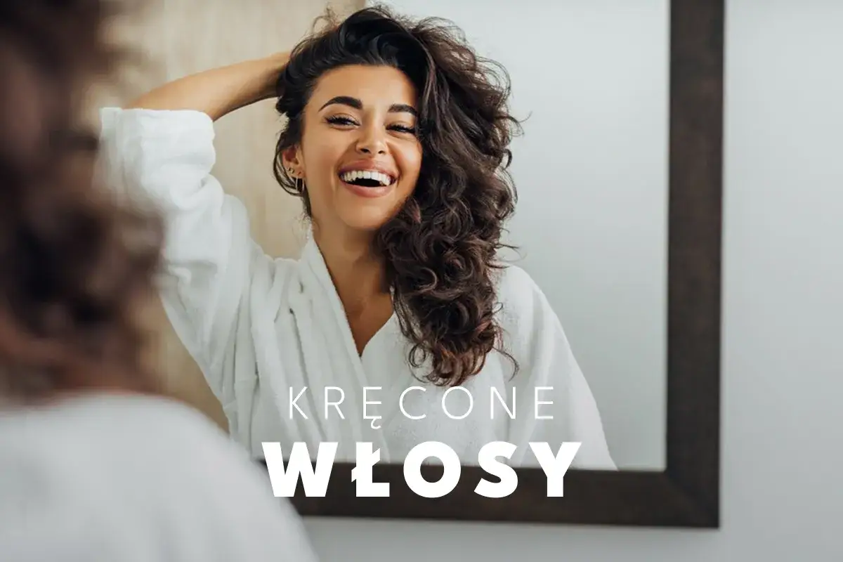 Uśmiechnięta kobieta w szlafroku podziwia swoje piękne, kręcone końcówki włosów w lustrze.