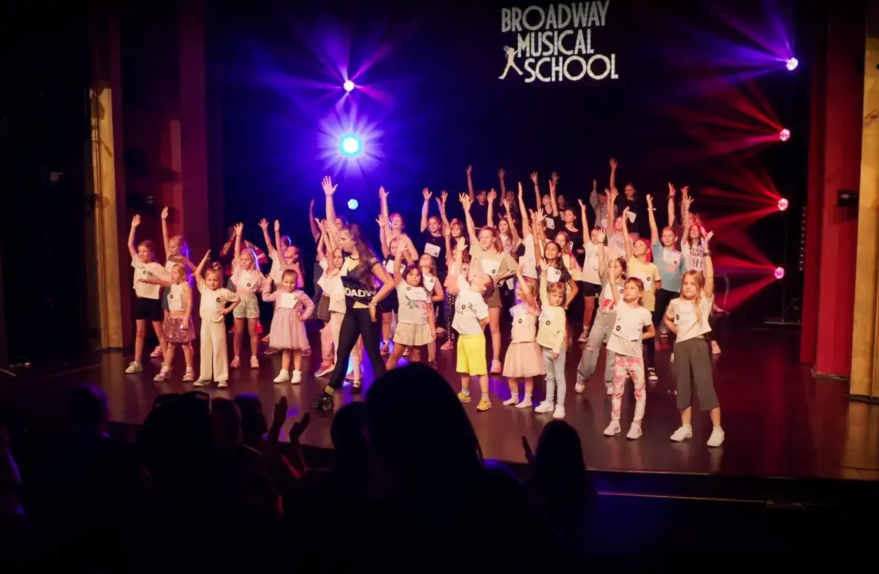 Dzieci z Broadway Musical School na scenie, przygotowujące się do najlepszych spektakli teatralnych.