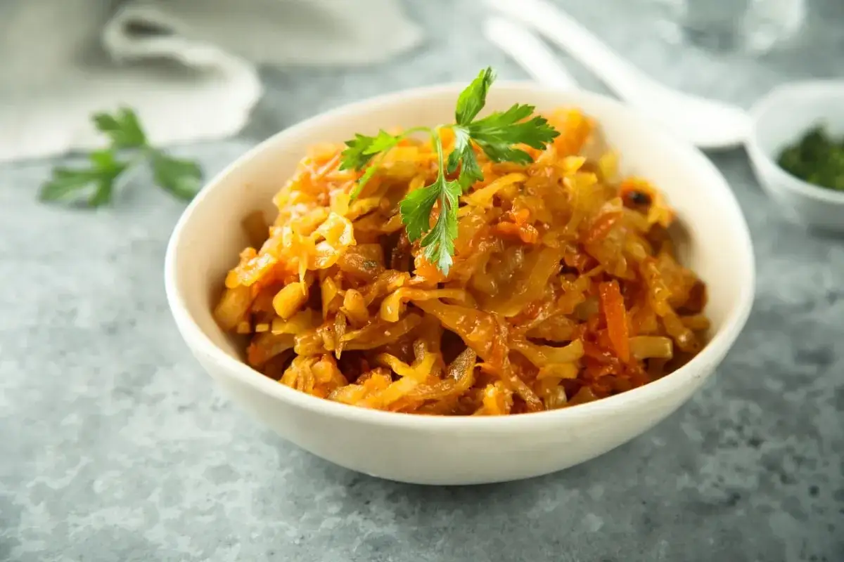 Duszona kapusta z marchewką, ozdobiona natką. Czy kapustę można mrozić? Tak, ta potrawa świetnie nadaje się do mrożenia.