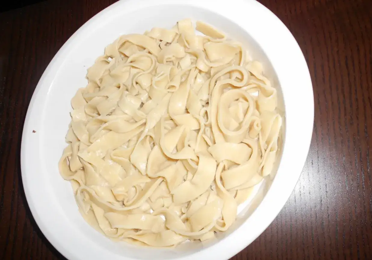 Świeżo ugotowany, domowy makaron tagliatelle w białej misce, gotowy do podania z ulubionym sosem.