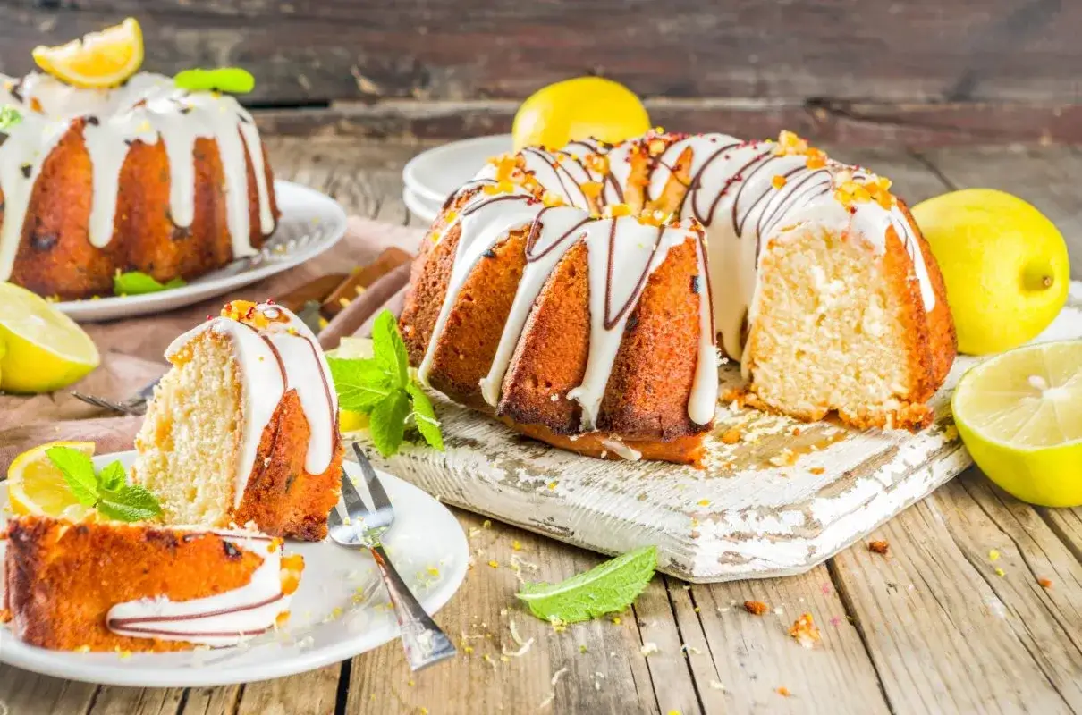 Pyszna babka na oleju z cytrynową polewą i kandyzowanymi sk&oacute;rkami, udekorowana miętą.