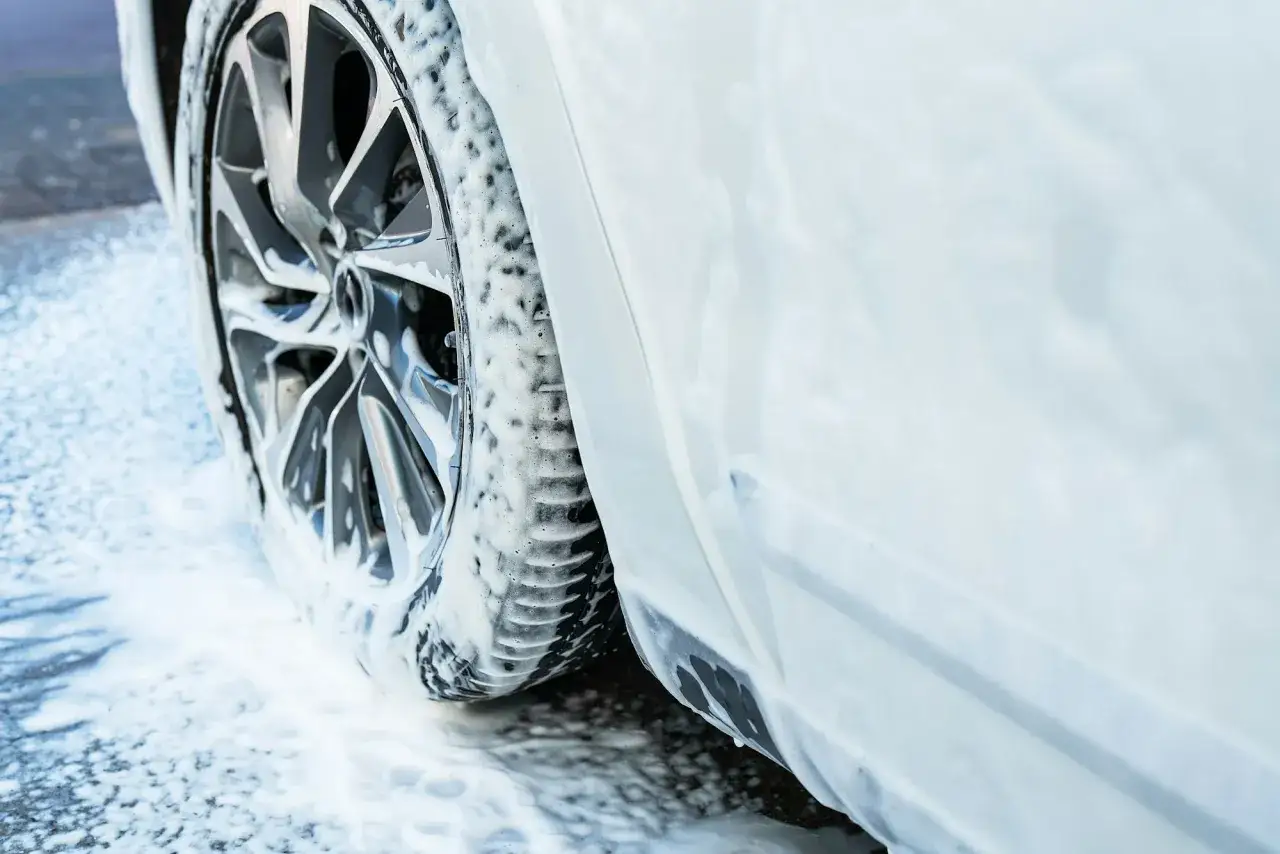 Białe auto pokryte pianą na myjni bezdotykowej. Zobacz, jak myć auto na myjni bezdotykowej, by lśniło czystością.