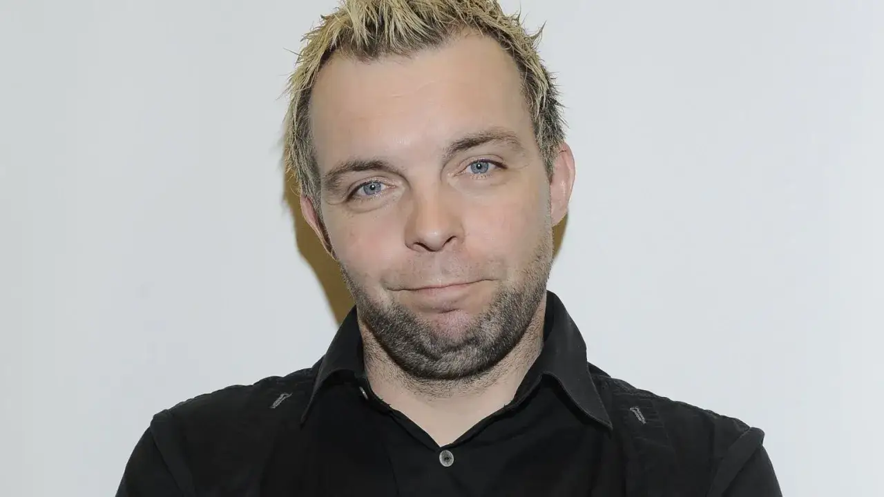 Marcin W&oacute;jcik z kabaretu Ani Mru-Mru, z charakterystyczną fryzurą i niebieskimi oczami, w czarnej koszuli.