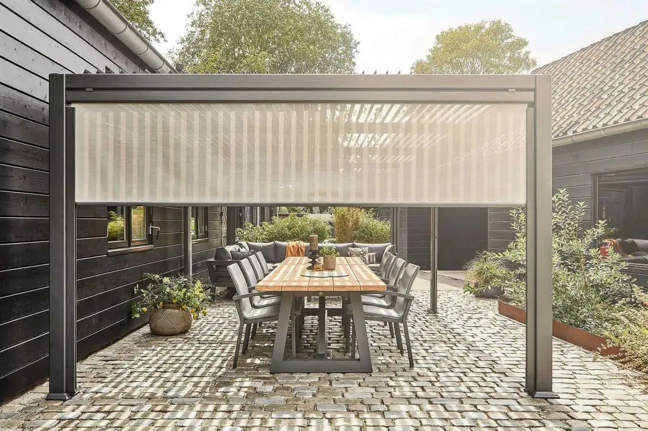 Nowy spos&oacute;b, jak osłonić taras od wiatru: nowoczesna pergola z zasłoną przeciwwiatrową, tworząca przytulną strefę relaksu z jadalnią.