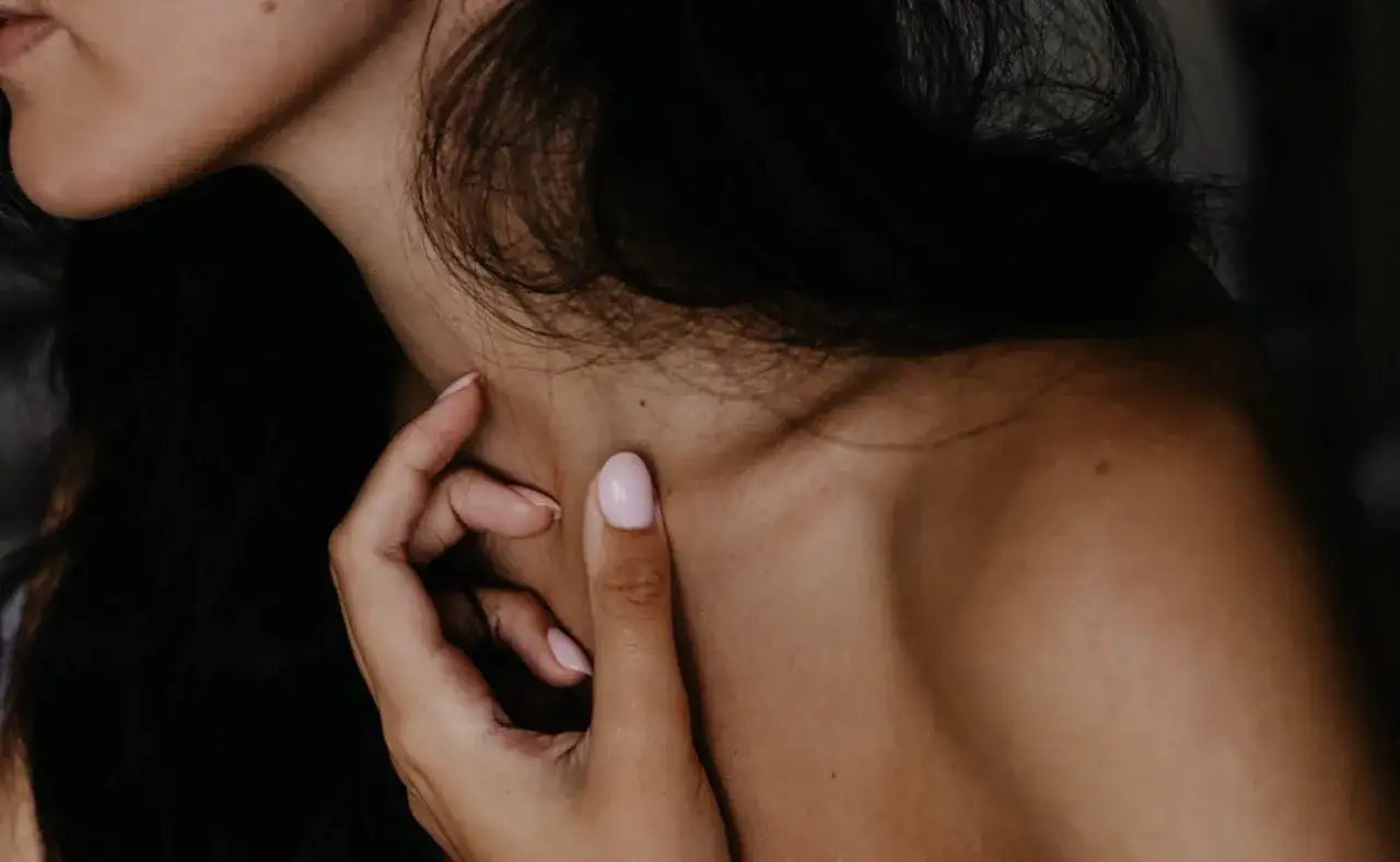 Delikatny dotyk dłoni na szyi, odkrywający subtelne strefy erogenne u kobiet.