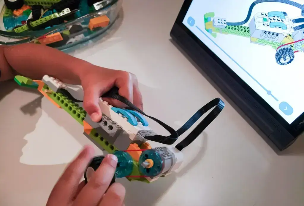 instruktor pomaga dziecku programować robota z Lego na tablecie