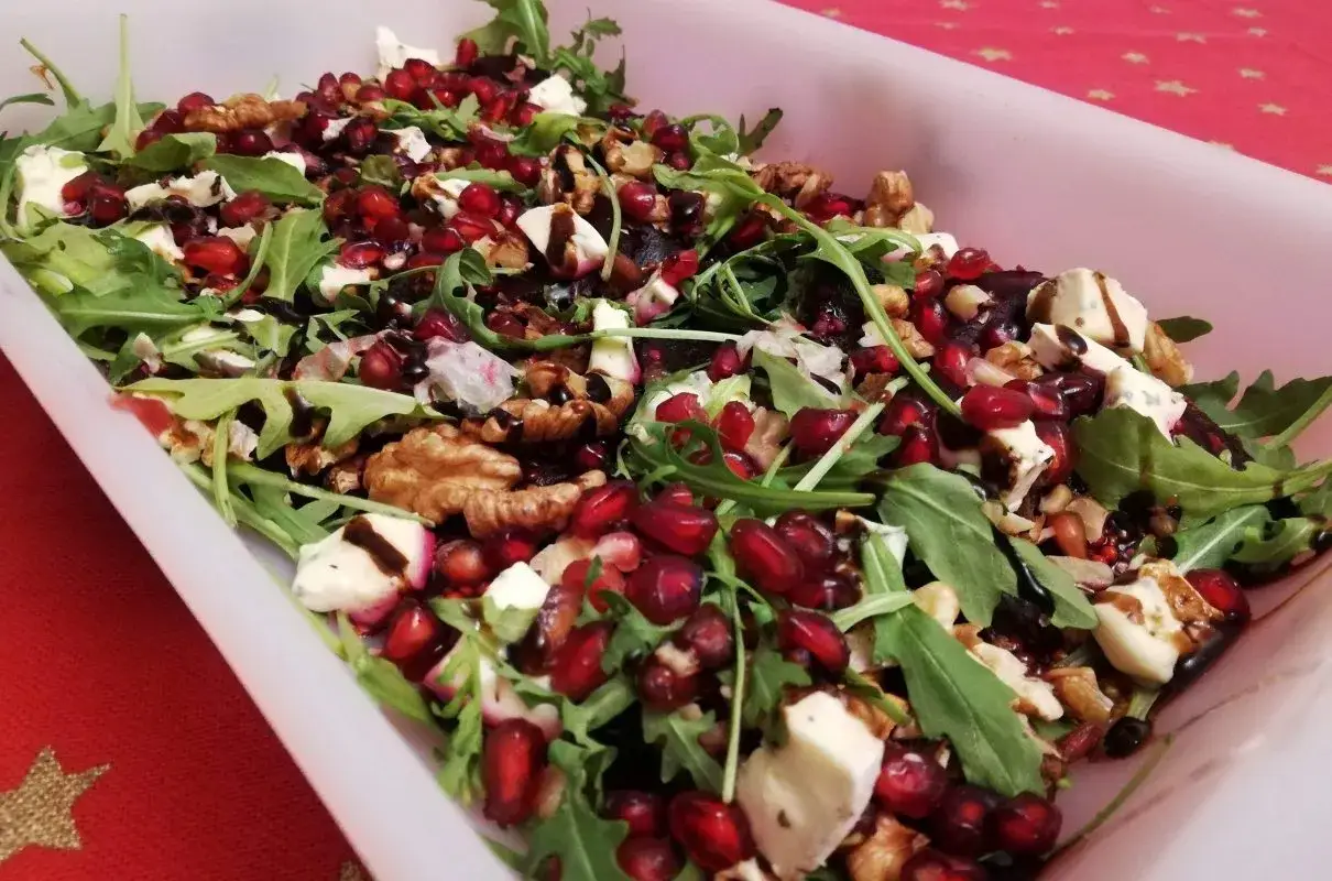 Pyszna sałatka z rukolą, serem pleśniowym, orzechami i soczystymi ziarnami granatu, polana sosem balsamicznym.