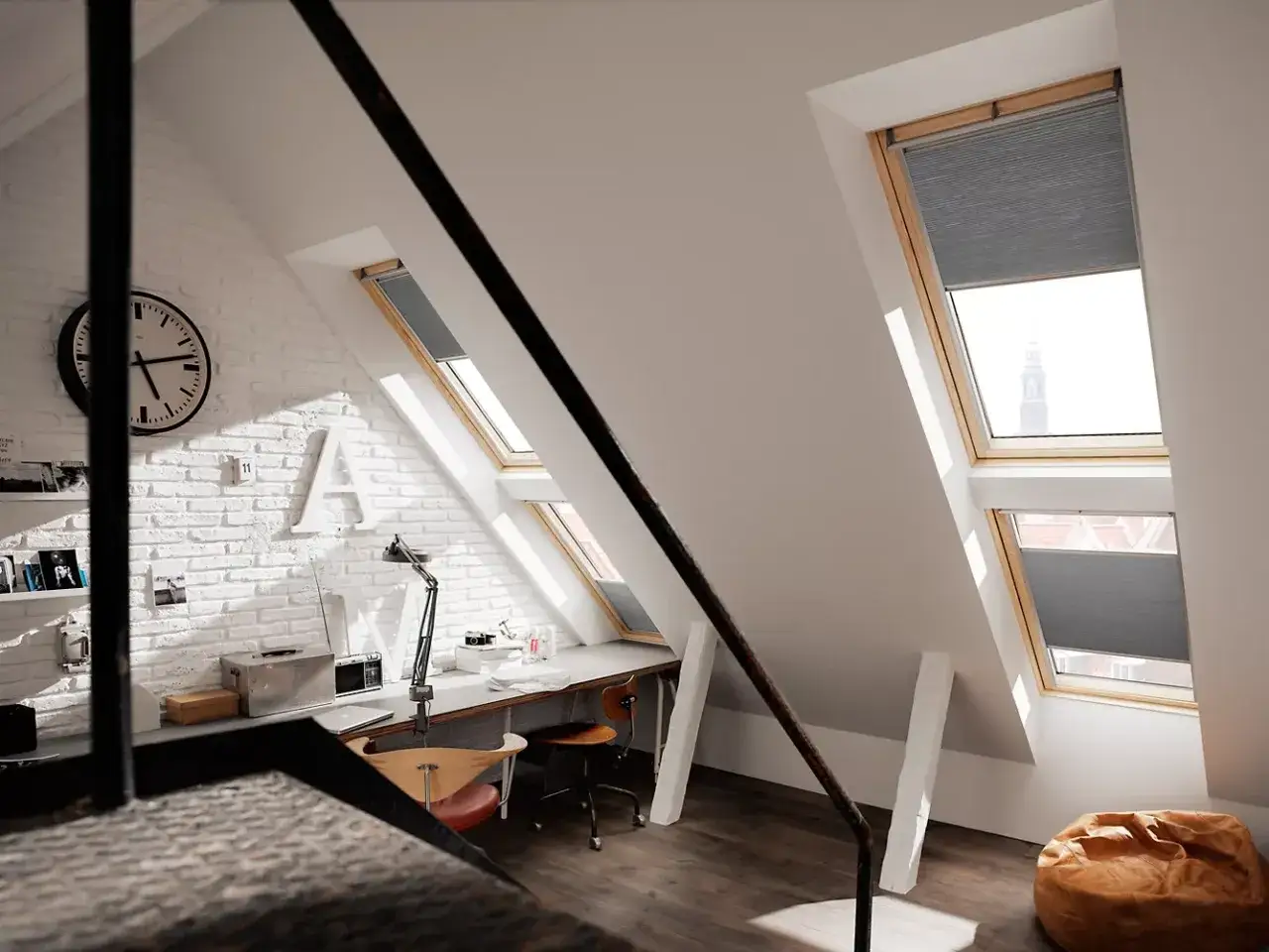 Pok&oacute;j na poddaszu z oknami dachowymi. Wnętrze sprzyja pracy, a widok z okna może pom&oacute;c w rozważaniach, jak obliczyć kąt nachylenia dachu.