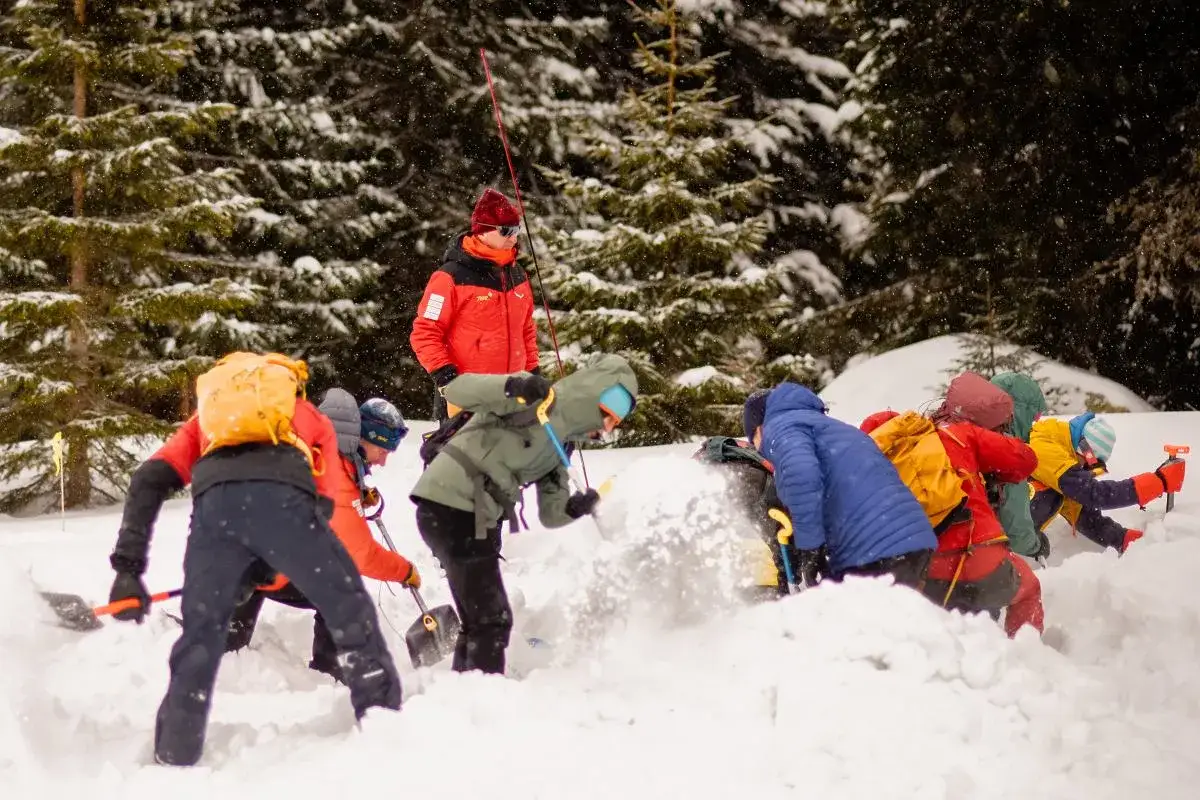 Ratownicy TOPR ćwiczą akcję ratunkową po lawinie w Tatrach. Grupa ludzi w zimowych ubraniach i z plecakami odkopuje zasypanych.