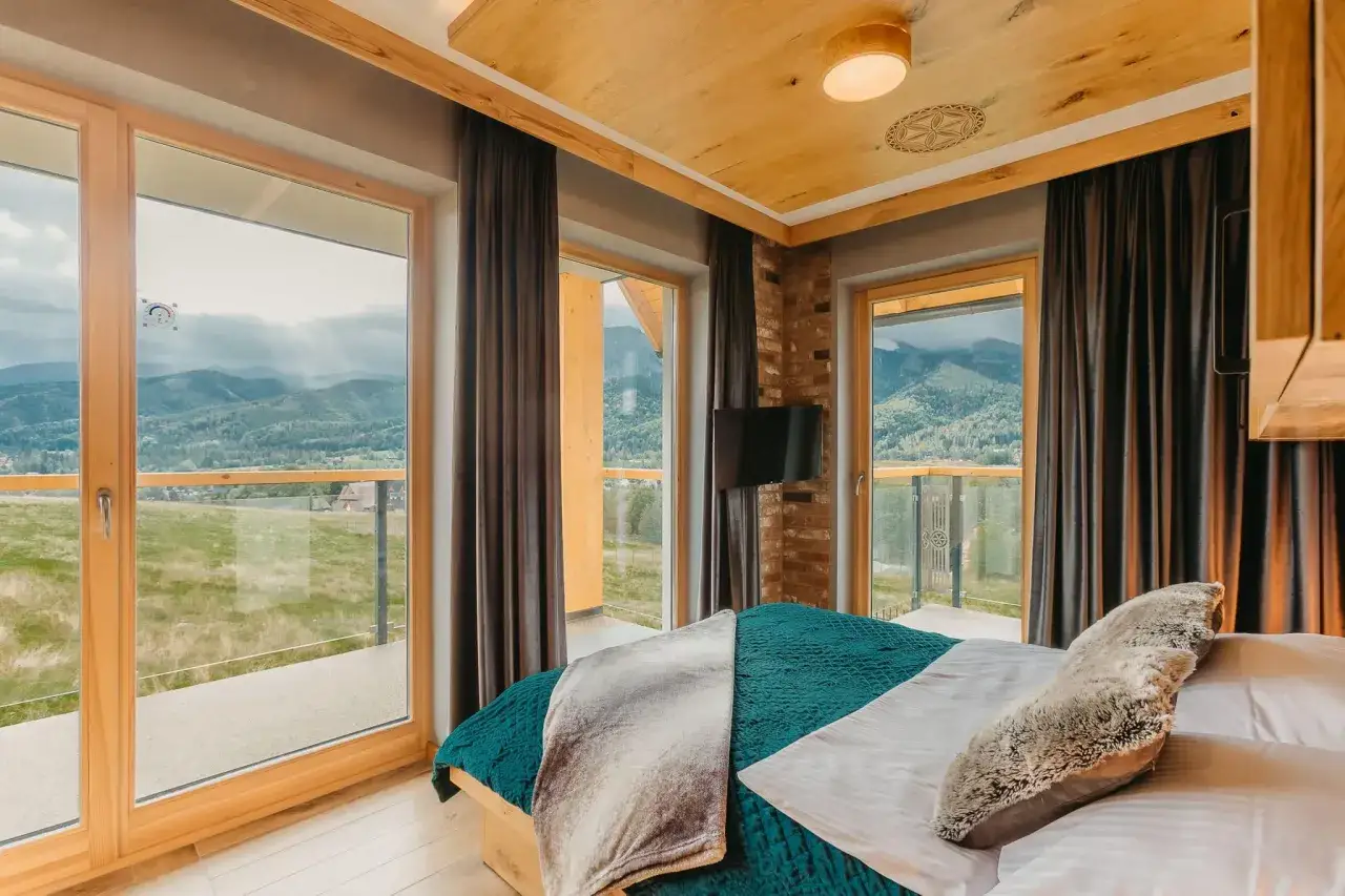 Przytulne pokoje i apartamenty Wierchy Zakopane z widokiem na g&oacute;ry. Drewniane wykończenia, wygodne ł&oacute;żko i przestronny balkon.