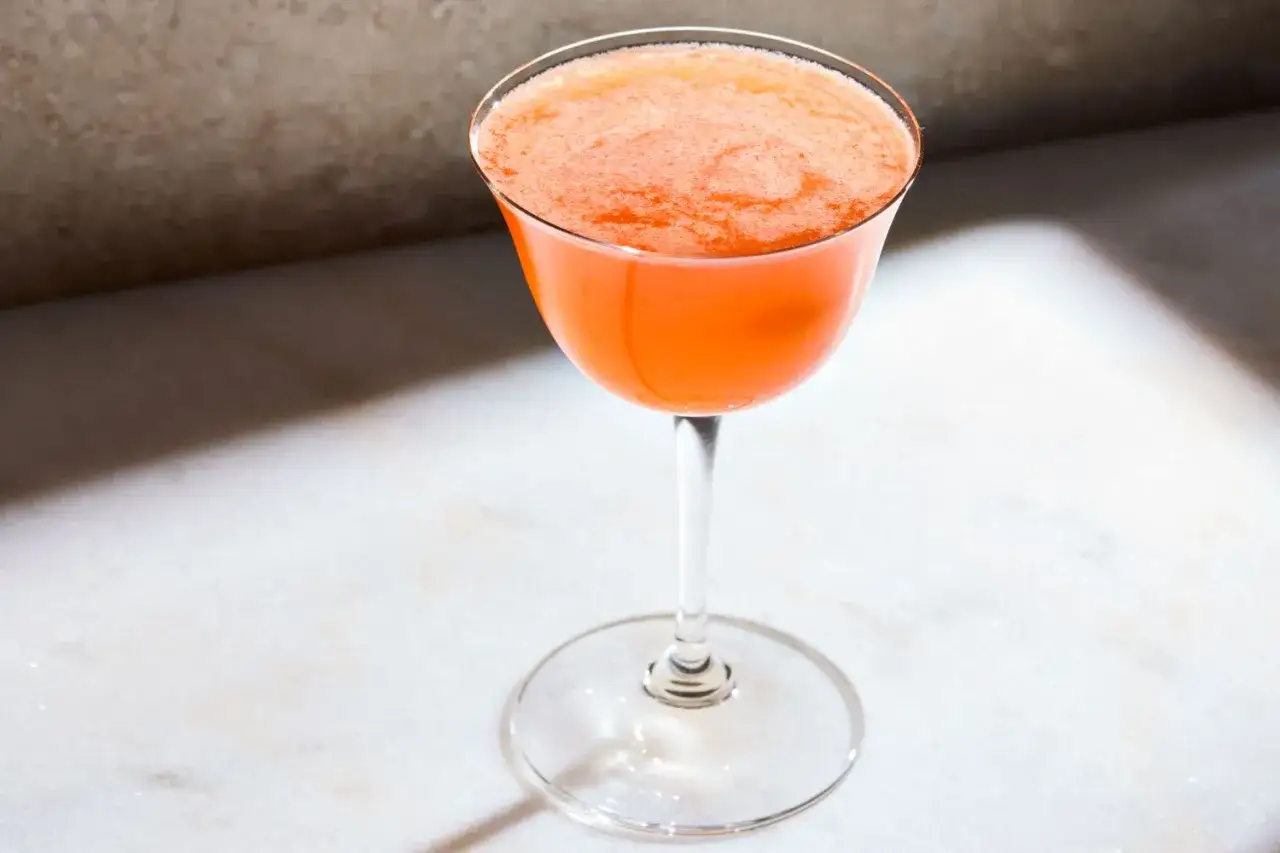 Orzeźwiający, pomarańczowy koktajl Paper Plane w eleganckim kieliszku, gotowy do lotu.