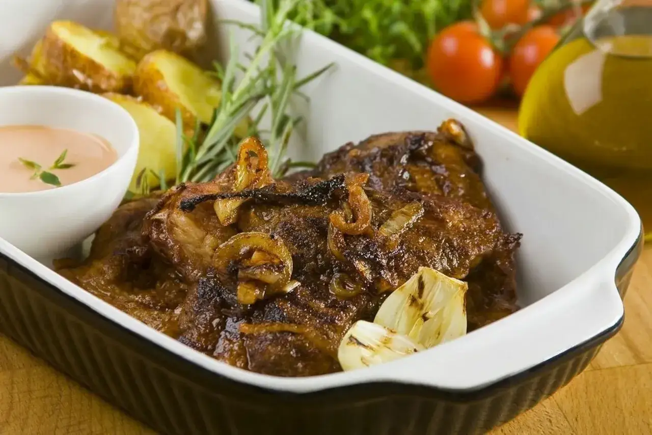 Soczysta karkówka z cebulką i czosnkiem, podana z pieczonymi ziemniakami i sosem. Idealne jakie przyprawy do karkówki!