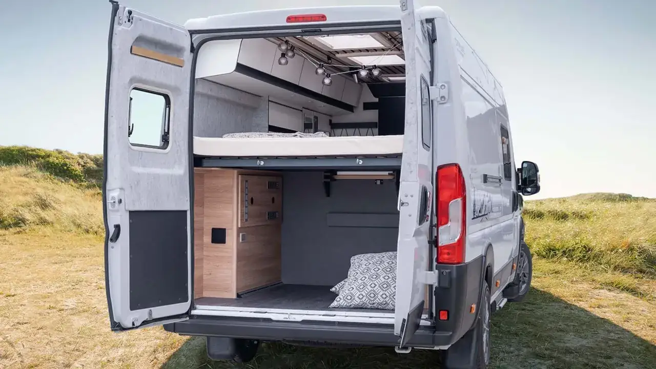 Mały kamper z łazienką, gotowy na przygodę. Wygodne łóżko, stylowe oświetlenie i przestrzeń do przechowywania.