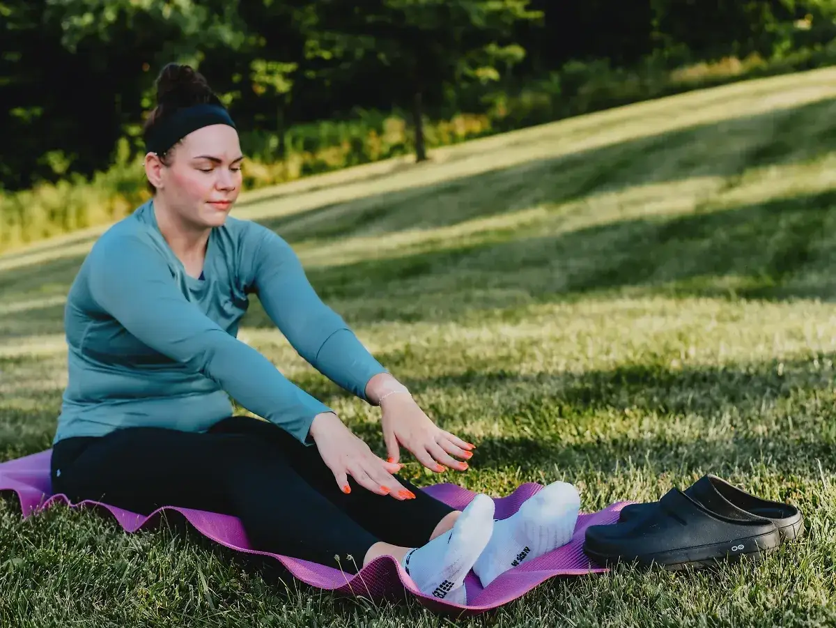 Kobieta na macie ćwiczy, przygotowując się do treningu. To pierwszy krok, by nauczyć się biegać.