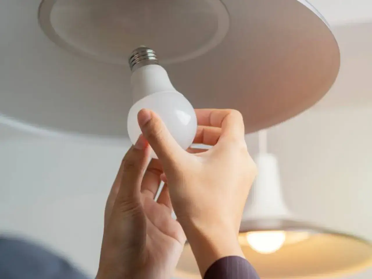 Ręce wymieniają żarówkę LED w lampie sufitowej. Prosty poradnik, jak wymienić żarówkę led.