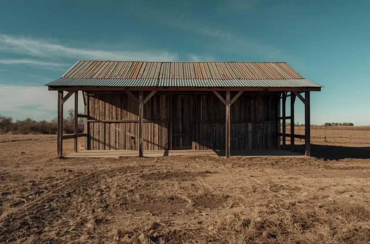 Dobudowa wiaty do budynku gospodarczego. Drewniana konstrukcja z falistym dachem, stojąca na pustkowiu.