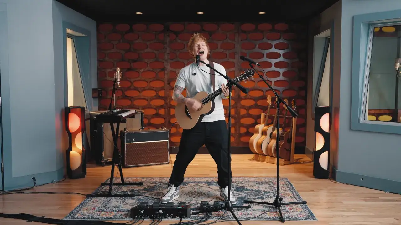 Ed Sheeran śpiewa i gra na gitarze akustycznej. Na czym gra Ed Sheeran? Na swoim charakterystycznym modelu gitary, z pętlą efekt&oacute;w pod stopami.