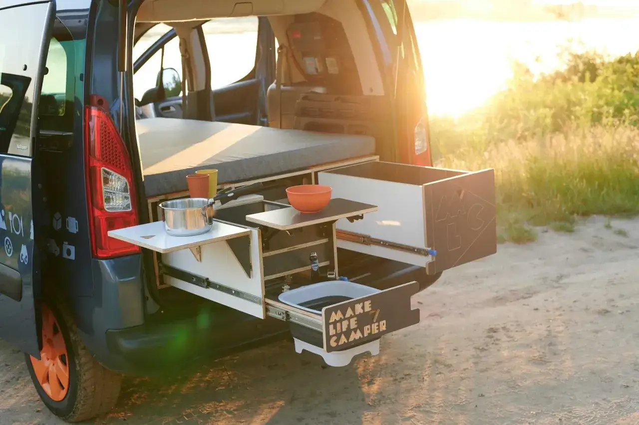Wnętrze buskampera z wysuwanym blatem, zlewem i naczyniami. Idealne na kempingowe przygody.