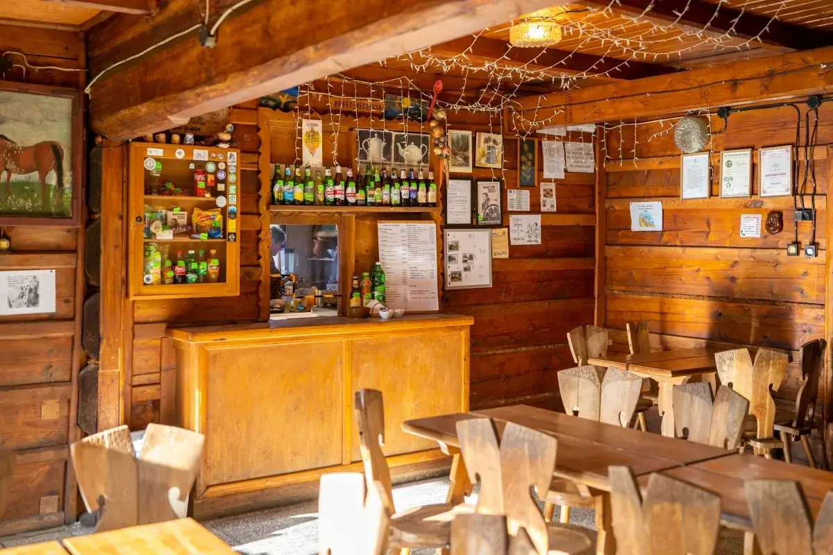 Wnętrze bac&oacute;wki w Jodł&oacute;wce Tuchowskiej. Drewniane stoły i krzesła, bar z napojami i przekąskami, ozdoby na ścianach.