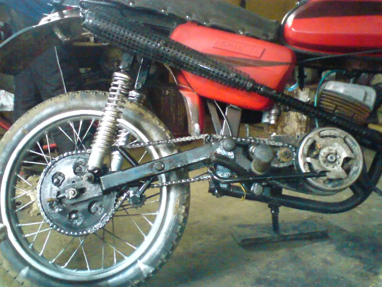 Detale motocykla 125 po chip tuningu: widoczna zębatka, amortyzator, czerwony bak i wydech.