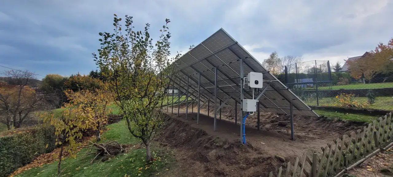 Solidna konstrukcja pod panele fotowoltaiczne na gruncie, gotowa do zbierania energii słonecznej. W tle jesienne drzewa i ogród.