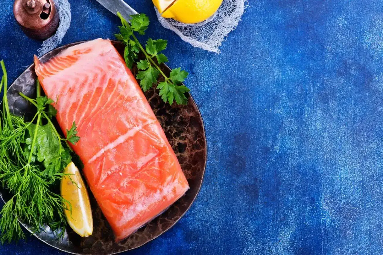 Świeży łosoś na talerzu z ziołami i cytryną. Czy łososia można mrozić? Tak, aby zachować jego świeżość.