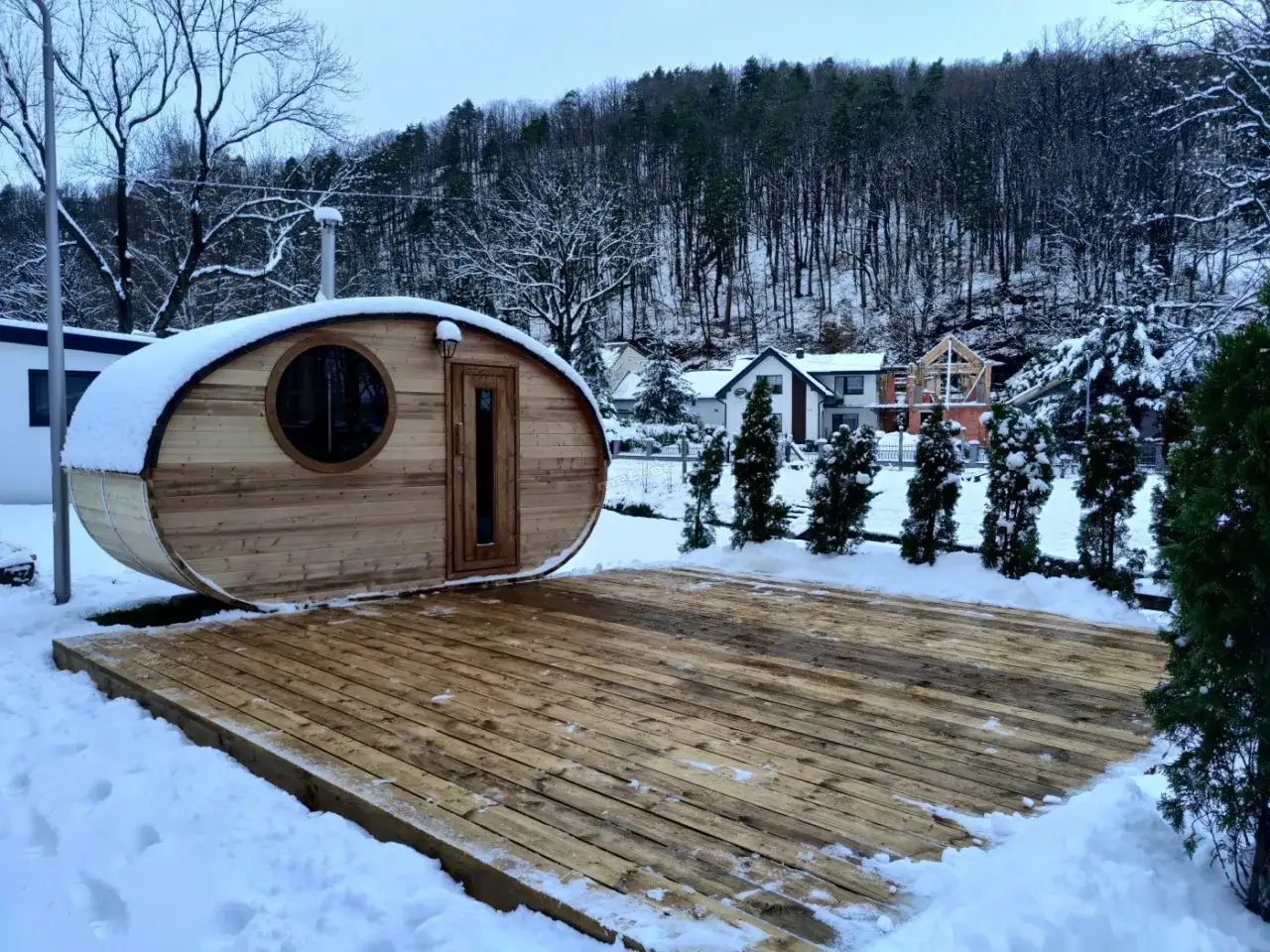 Drewniana beczka sauna, idealna na zimowy wypoczynek w osadzie Chmielaki. Otoczona śniegiem i lasem.