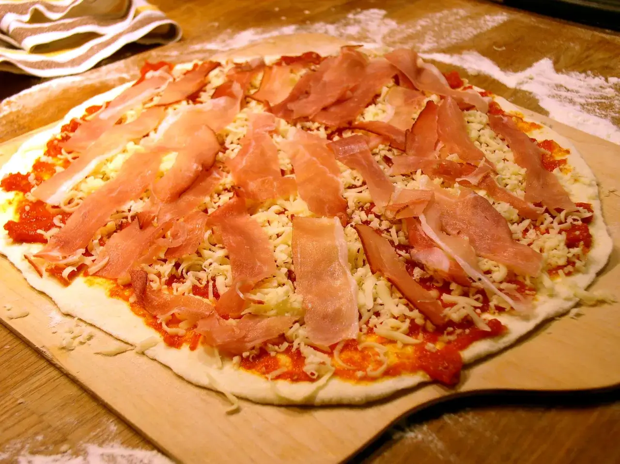 Niegotowa pizza rzymska z szynką i serem, gotowa do pieczenia. Idealny przepis na domową pizzę.