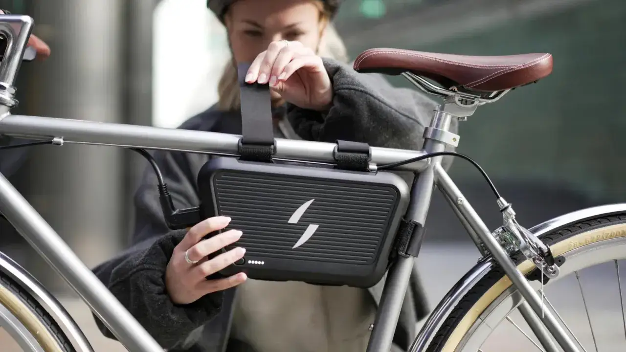 Kobieta montuje na rowerze czarną obudowę z symbolem pioruna. To zestaw do konwersji roweru 3000w, który zamieni Twój rower w elektryczny.