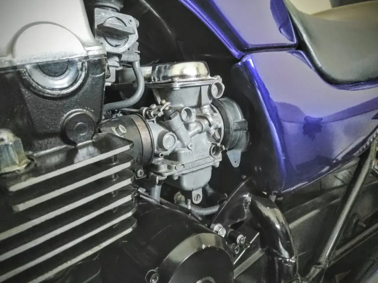 Silnik motocykla z gaźnikiem. Paliwo leci do filtra powietrza, bo coś jest nie tak z pływakiem lub iglicą.